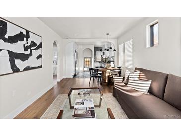 Open-concept living room, kitchen, and dining area featuring hardwood floors and abundant natural light at 3250 N Clayton St, Denver, CO 80205