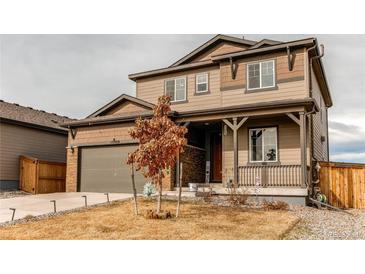 Two-story home with brown siding, stone accents, covered porch, and attached garage at 15920 Hayloft Ln, Parker, CO 80134