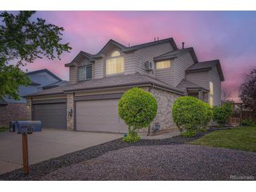 Charming home with a two-car garage, gray brick accents, and well-maintained landscaping at dusk at 401 W 114Th Pl, Northglenn, CO 80234