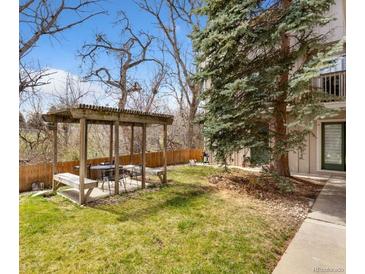 Landscaped backyard features a wooden pergola with seating area and lush lawn at 1607 Cottonwood Dr # 14, Louisville, CO 80027