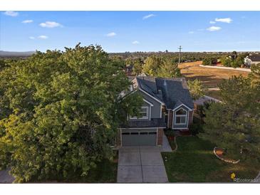 Aerial view of a two-story house with a landscaped yard and city views in the background at 7291 Palisade Dr, Highlands Ranch, CO 80130