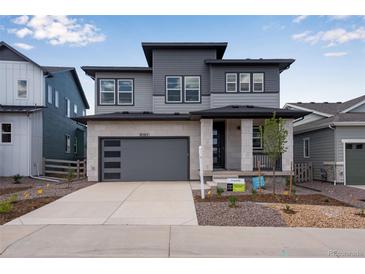 Attractive two-story home with a stone-accented facade, gray siding, and a spacious two car garage at 8585 Eckley St, Littleton, CO 80125