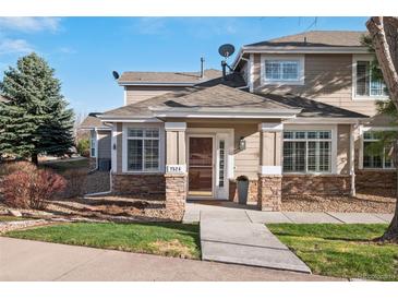 Charming townhouse entrance featuring stone accents, well-maintained landscaping, and a welcoming front door at 7524 Pineridge Trl, Castle Pines, CO 80108