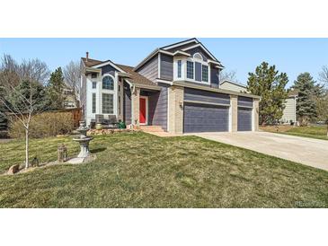 Charming home with a well-manicured lawn, a red door, and a three-car garage at 16442 Bluebonnet Dr, Parker, CO 80134