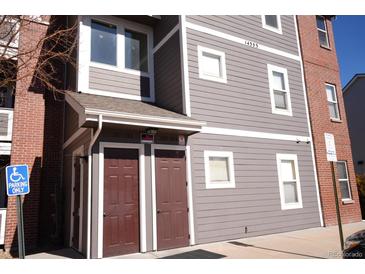 Multi-story condo building with gray siding, brick accents, and clearly marked unit entrances at 14353 E 1St Dr # 201, Aurora, CO 80011