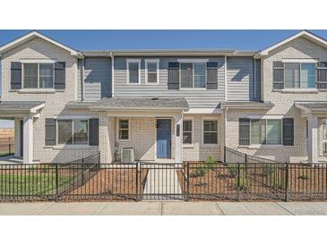 Charming townhome featuring a fenced yard, light brick and blue accent door at 27742 E 1St Ave, Aurora, CO 80018