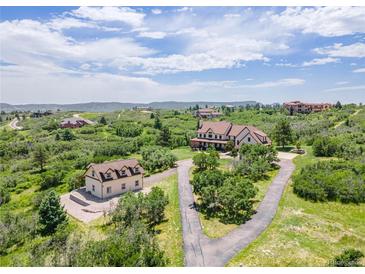 Expansive aerial view of an estate, showcasing lush landscaping, a guest house, and stunning mountain views at 1091 Colt Cir, Castle Rock, CO 80109