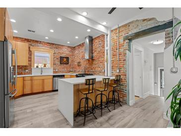 Stylish kitchen with brick accent wall, modern island, stainless steel appliances, and updated fixtures at 3354 Vallejo St, Denver, CO 80211