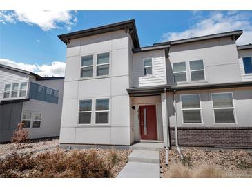 Modern two-story home with red door and low maintenance landscaping of small rocks and bushes at 19197 E 64Th Ave, Denver, CO 80249