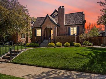 Charming brick home featuring an arched entryway and beautifully landscaped front yard at sunset at 1024 S Columbine St, Denver, CO 80209