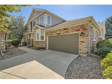 Exterior view of a tan two-story home, showcasing a two-car garage with a stone facade at 3546 Broadlands Ln # 102, Broomfield, CO 80023