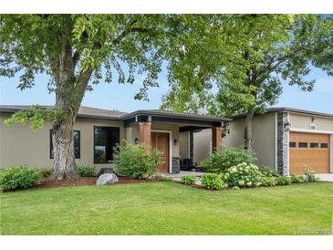 Charming home featuring a covered entryway with wooden pillars and mature landscaping at 8250 W 63Rd Ave, Arvada, CO 80004