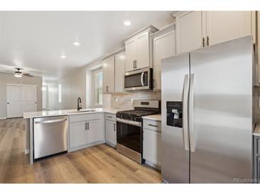 Modern kitchen featuring stainless steel appliances, white cabinetry, and quartz countertops at 9462 Yampa Ct, Commerce City, CO 80022