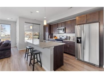 Modern kitchen boasts stainless steel appliances, granite countertops, and wood cabinets at 5110 E 64Th Ave, Commerce City, CO 80022