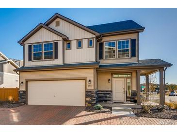 Charming two-story home with tan siding, dark shutters and a covered porch, blending modern and traditional design elements at 10512 Truckee St, Commerce City, CO 80022