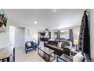 Open-concept living room showcases contemporary decor and transitions seamlessly into the kitchen and dining area at 7020 Avrum Dr, Denver, CO 80221
