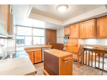 Charming kitchen featuring custom wood cabinets and a bright window over the sink at 10991 E Vassar Dr, Aurora, CO 80014