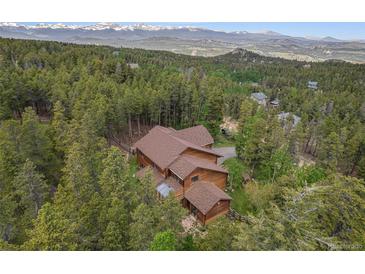 Stunning aerial view of mountain home surrounded by lush greenery and views of snow capped mountains in the background at 5 Ronnie Rd, Golden, CO 80403