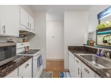 Galley kitchen features white cabinetry, granite countertops, and modern appliances at 2281 S Vaughn Way # 316A, Aurora, CO 80014