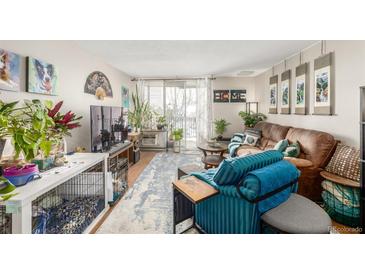 Comfortable living room with plants, a cozy couch, a television, and a sliding glass door to a balcony at 2281 S Vaughn Way # 316A, Aurora, CO 80014