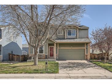 Two-story home with well-maintained lawn and two-car garage, featuring a red front door and stone accents at 9615 Lansing Cir, Commerce City, CO 80022