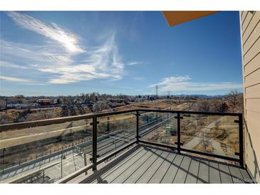 Balcony with clear glass railing and view of railroad tracks, walking path, and mountains beyond at 1208 N Quitman St # 402, Denver, CO 80204
