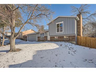 Gray exterior boasts brick accents and a spacious yard with a wooden fence at 16046 E Harvard Ave, Aurora, CO 80013