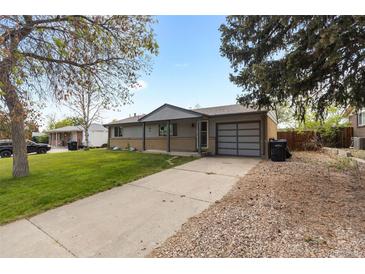 Charming single-story home featuring a well-manicured lawn and a long, paved driveway leading to the garage at 8305 Eaton Way, Arvada, CO 80003