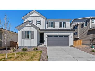 Charming two-story home with white siding, a gray garage door, and well-maintained landscaping at 9175 Uravan Ct, Commerce City, CO 80022