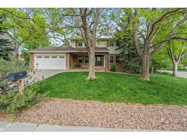 Charming two-story home with brick accents, mature trees, lush lawn, and a two car garage at 6222 S Ames Ct, Littleton, CO 80123