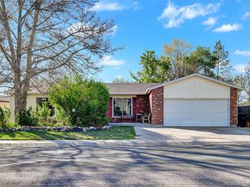 Charming one-story home with brick and siding, featuring a well-maintained front yard and attached two-car garage at 10878 Grange Creek Dr, Thornton, CO 80233