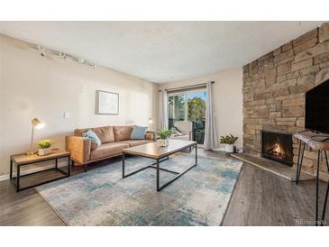 Inviting living room featuring a stone fireplace, plush sofa, and abundant natural light at 430 Zang St # 4-102, Lakewood, CO 80228