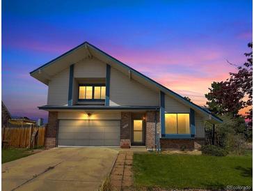 Charming two-story home with well-maintained lawn, brick accents, and an attached two-car garage during a scenic sunset at 8133 W Quarto Ave, Littleton, CO 80128