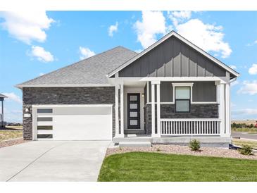 Beautiful home with a gray exterior, stone accents, a well-manicured lawn, and a two car garage at 42966 Colonial Trl, Elizabeth, CO 80107