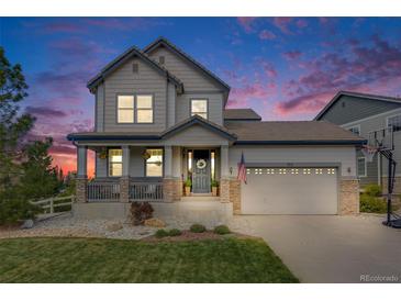 Beautiful two-story home with a welcoming front porch and well-maintained landscaping at dusk at 703 Tiger Lily Way, Highlands Ranch, CO 80126