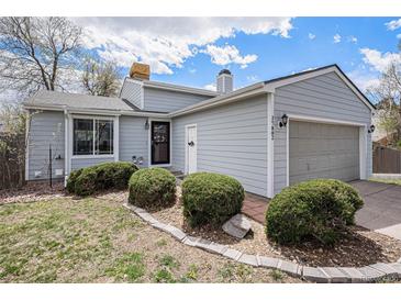 Charming home showcasing its light blue siding, well-manicured landscaping, and attached two-car garage at 17802 E Bates Ave, Aurora, CO 80013
