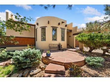 Inviting front entrance with a stone patio, bench, and charming Southwestern architectural details at 6457 Willow Broom Trl, Littleton, CO 80125