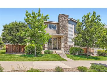 Charming two-story home featuring stone accents, a well-manicured lawn, and lush greenery at 15437 W 95Th Ave, Arvada, CO 80007