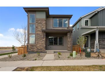 Charming two-story home with a stone facade, complemented by modern windows and professional landscaping at 21044 E 63Rd Dr, Aurora, CO 80019