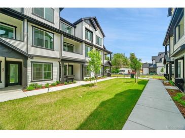 Modern two-story townhouse featuring a well-manicured lawn and a sidewalk leading to the entrance at 8530 W 52Nd Ave # A1, Arvada, CO 80002