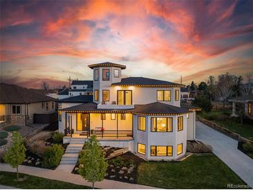 Stunning two-story home featuring a unique turret and welcoming front porch against a colorful sunset backdrop at 8240 W Tennessee Ave, Lakewood, CO 80226