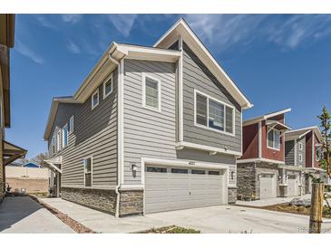New construction home featuring a two-car garage with stone accents and gray horizontal siding at 4327 E 98Th Pl, Thornton, CO 80229