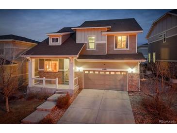 Two-story home featuring a two-car garage, covered front porch with brick accents at 26881 E Roxbury Pl, Aurora, CO 80016