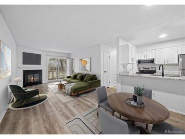 Bright living room features a fireplace, wood floors, and a sliding glass door to a balcony at 14720 E Kentucky Dr # 612, Aurora, CO 80012