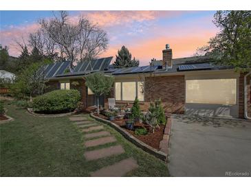 Brick home with solar panels, landscaped yard, and flagstone walkway leading to the front door at dusk at 805 Union Ave, Boulder, CO 80304