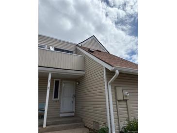 Charming home featuring light beige siding, a brown roof, and a cozy front porch entry at 2491 S Xanadu Way # A, Aurora, CO 80014