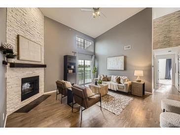 Inviting living room boasts a brick fireplace, vaulted ceilings, and a sliding door to the outdoor balcony at 9481 E Mansfield Ave # 301, Aurora, CO 80014