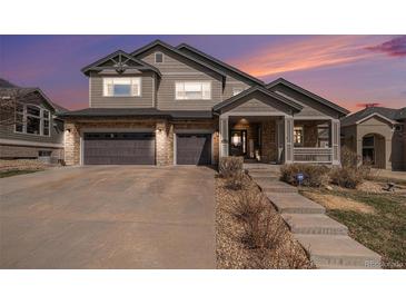 Charming two-story home featuring stone accents, a covered porch, and a spacious two-car garage at 26989 E Friend Pl, Aurora, CO 80016