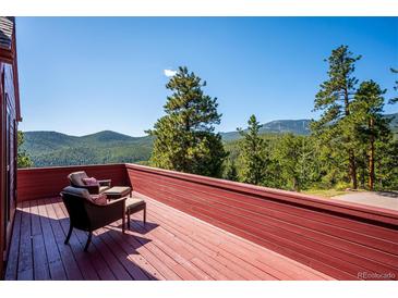 Inviting red wood deck offers stunning mountain and tree line views with seating for relaxing at 7350 Timber Trail Rd, Evergreen, CO 80439