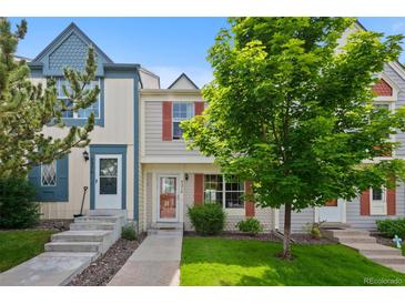 Inviting townhome featuring a well-maintained lawn and a charming facade with red shutters and a mature shade tree at 9278 W Ontario Dr, Littleton, CO 80128